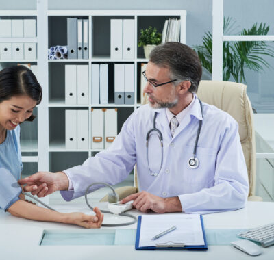 Checking pressure Mature doctor checking blood pressure of female patient